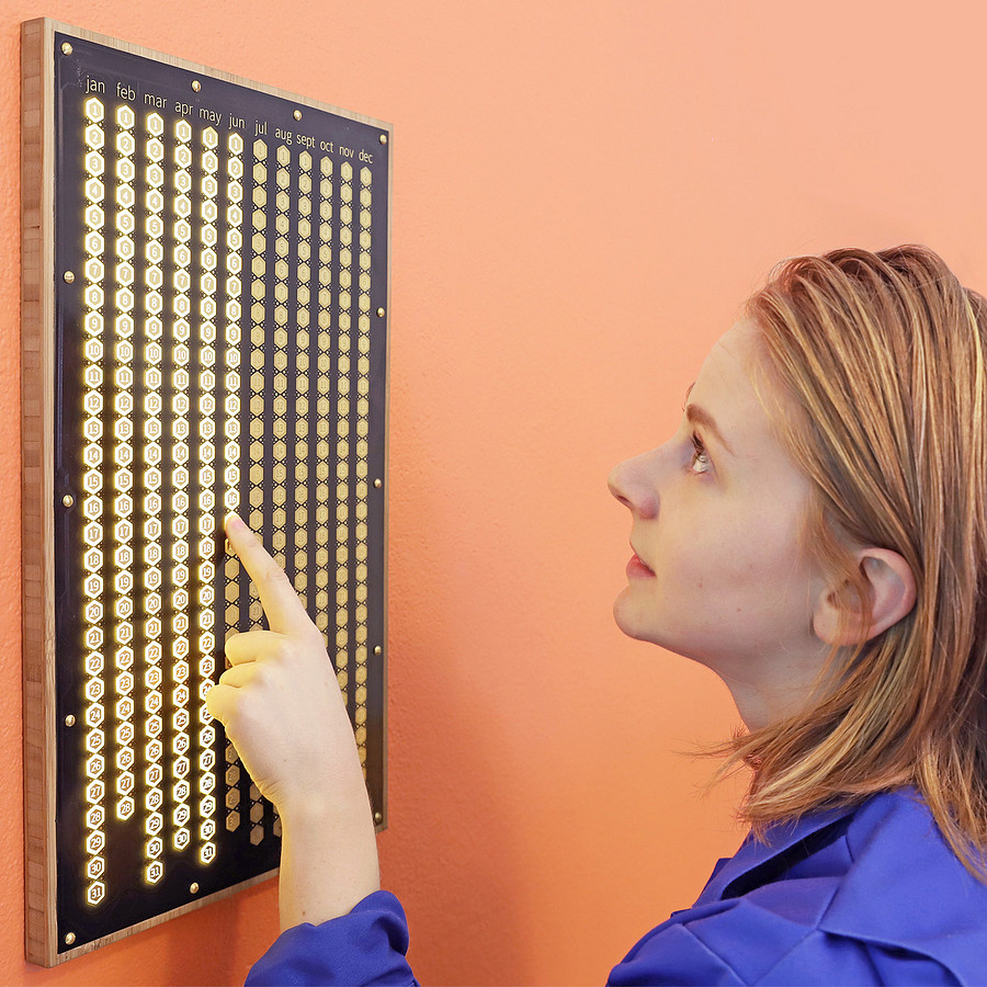 Simone looking at the Everyday Calendar, a huge wall-mounted board that has a button for every day of the year. She's pushing a button to make it light up.
